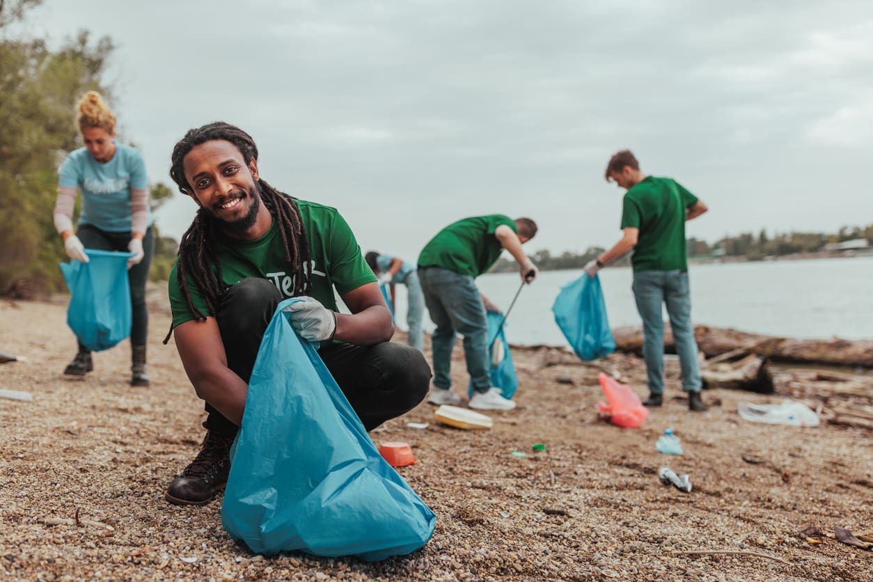 Smiling volunteer cleaning beach with group.