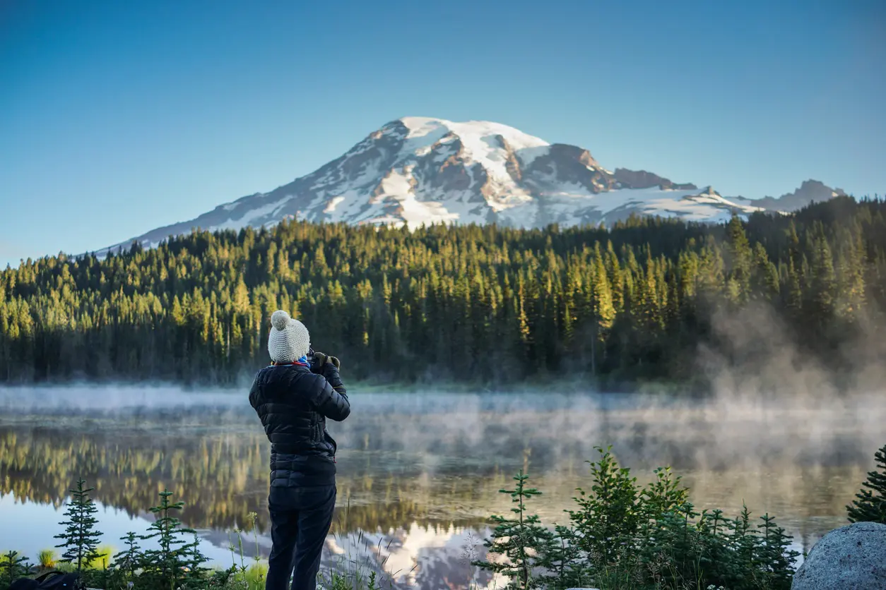 Person photographs misty mountain lake.