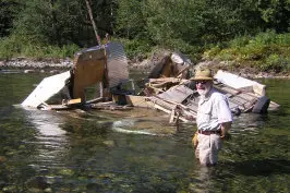 A man standing in the water near some debris.